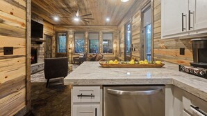 Ein modernes Interieur einer Blockhütte mit Küche, Essbereich und Kamin.