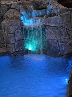 Una piscina con una cascada rodeada de paredes de roca.