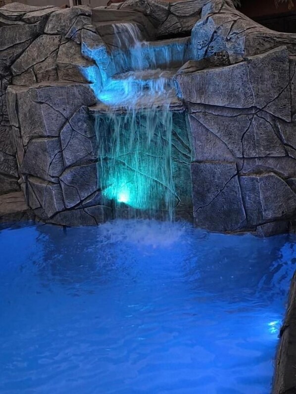 Una piscina con una cascada rodeada de paredes de roca.