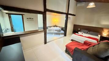 Una habitación de hotel con cama, sofá, una mesita y vistas a un balcón.
