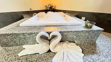Casa de banho com uma grande lavatório de granito, duas toalhas dobradas em forma de cisnes e uma pequena tigela decorativa.