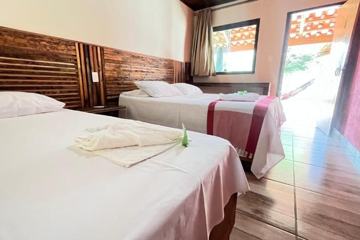 A hotel room with two beds, wooden headboard, and a view of the outside.