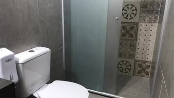 Un baño con inodoro, cabina de ducha y azulejos estampados.