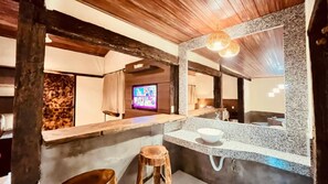 A bathroom with a wooden ceiling, a large mirror, a sink, and a stool. - Pousada Flor de Pequi (Santana do Riacho)