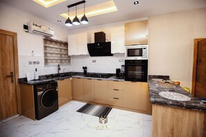 A modern kitchen with a built-in washing machine, a microwave, and a stove. - Bubbles Apartment - Modern 2BR, Games Lounge, Sleeps 4 – Yaba, Lagos (Lagos)