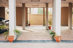 A covered outdoor area with columns, potted plants, and a car parked to the side. - Bubbles Apartment - Modern 2BR, Games Lounge, Sleeps 4 – Yaba, Lagos (Lagos)