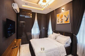 Una moderna camera d'albergo con un letto, una televisione, una scrivania e un bagno.