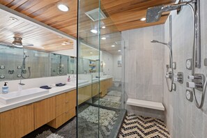 Een moderne badkamer met een douchecabine van glas, een houten wastafelmeubel en een betegelde vloer.