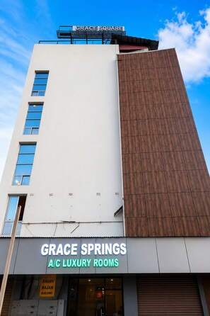 Un edificio con un cartel que indica 'GRACE SQUARE' y 'GRACE SPRINGS HABITACIONES DE LUJO CON AIRE ACONDICIONADO', señalando un hotel o establecimiento de alojamiento.