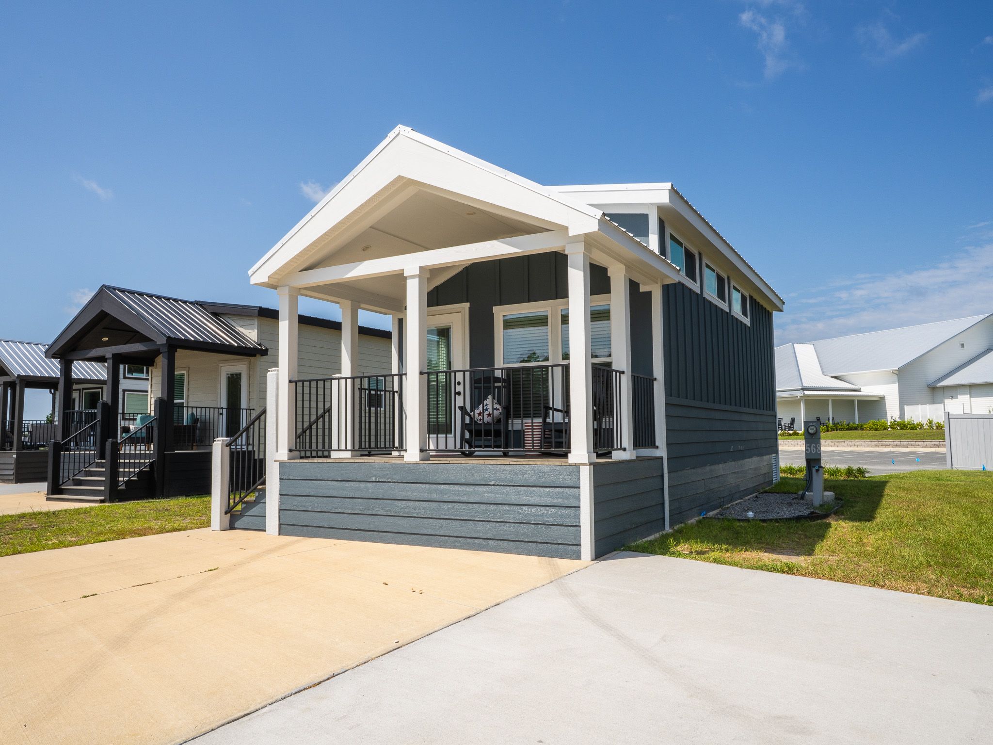 A modern single-story house with a covered porch, a front yard, and a clear blue sky.