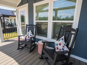 A porch with two rocking chairs, each with a star-patterned pillow, and a striped stool. - The Hotel Cabin - Bold Americana Suite - Pool - Hot Tub - Gym - Bar - Lake (Crystal River)