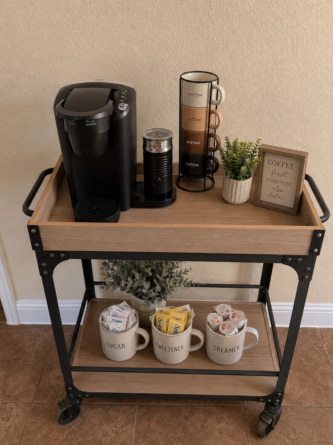 Een koffiehoek met een koffiezetapparaat, een thermoskan, een mok, een plant en een bordje op een houten karretje.