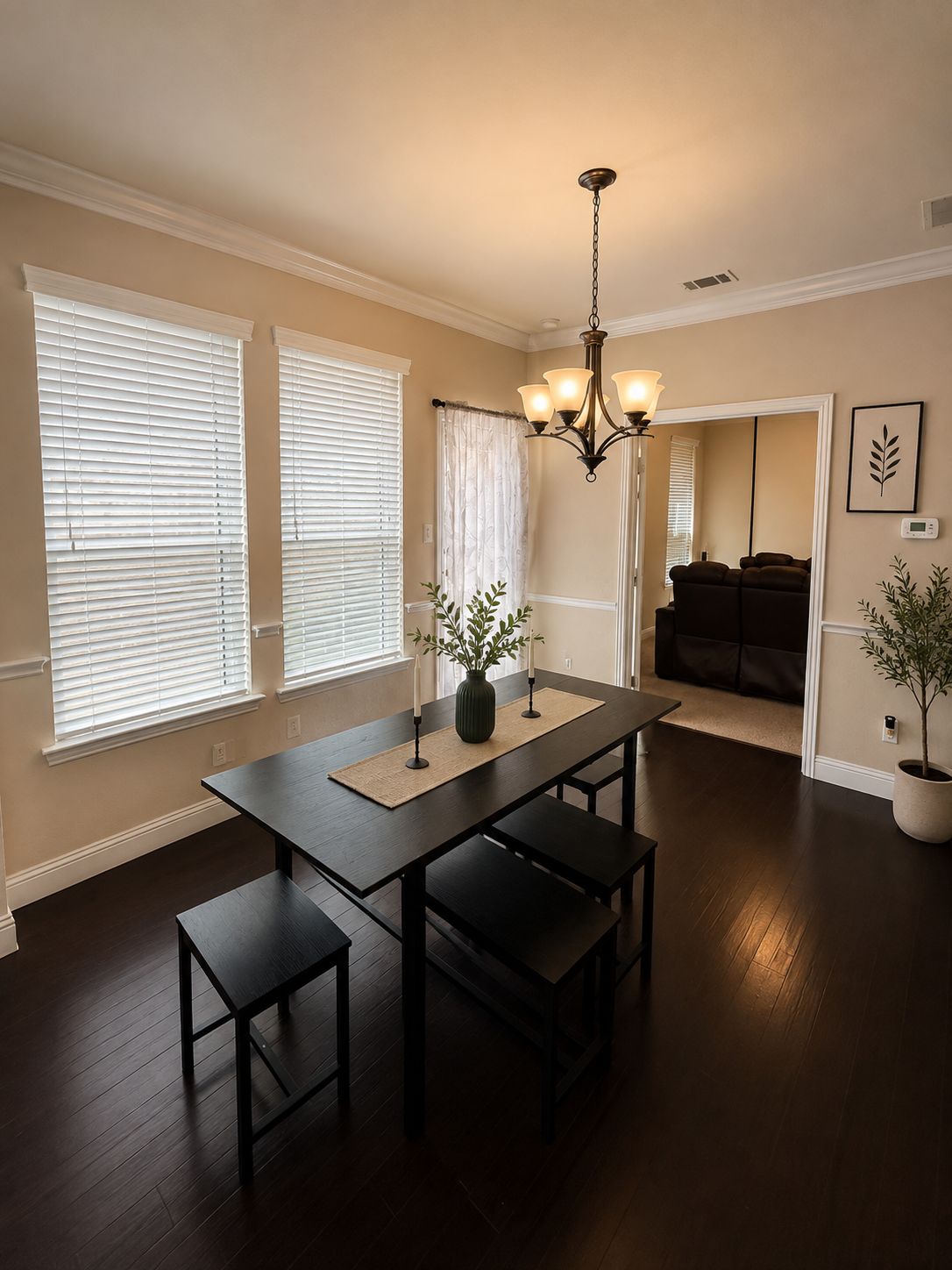 A dining area with a table, benches, a vase with plants, and a chandelier.
