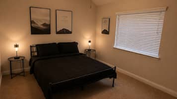 A bedroom with a bed, two bedside tables, a ceiling fan, and a window with blinds.