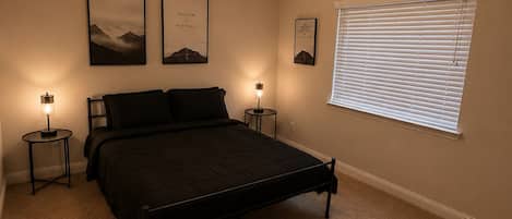 A bedroom with a bed, two bedside tables, a ceiling fan, and a window with blinds.