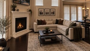 Amplia sala de estar con chimenea, un sofá grande, una mesa de centro y un ventilador de techo.