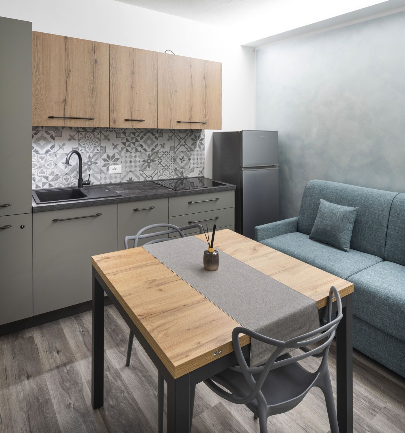 Cocina compacta con mesa, sillas, refrigerador y sofá.