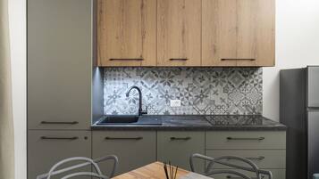 A modern kitchen with grey cabinets, a black faucet, and a patterned backsplash.