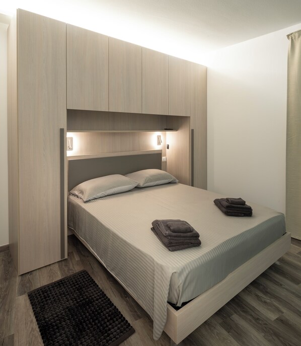 Un lit avec une tête de lit, des lampes de chevet, une table de chevet et un tapis foncé.