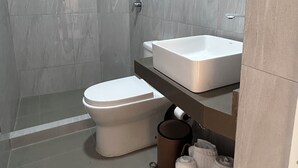 Een moderne badkamer met douche, toilet en wastafel.
