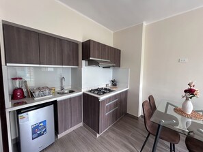 A compact kitchen with dark wood cabinets, a built-in stove, and a small refrigerator. - Apartment in Miraflores near Larcomar (Miraflores)