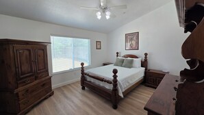 Una camera da letto con un letto grande, un'armadio in legno e una ventola a soffitto.