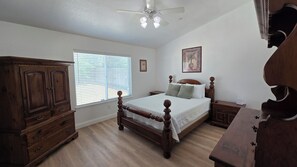 Ein Schlafzimmer mit einem großen Bett, einem Holzschrank und einem Deckenventilator.