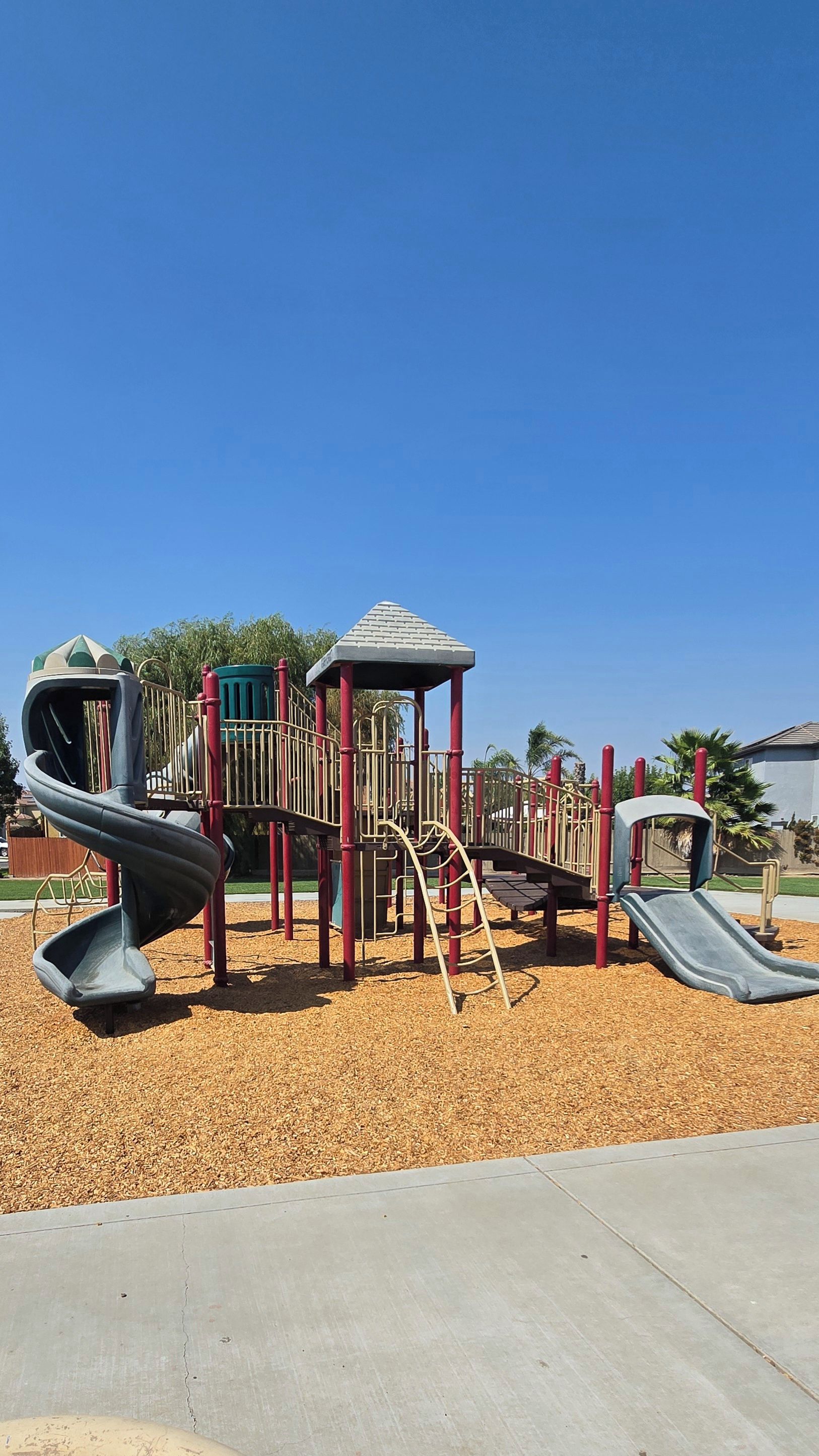 Un parque infantil con un tobogán, estructuras para escalar y una zona de juegos cubierta.