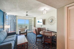 A hotel room with a balcony, a dining area, and a TV screen displaying 'Big Fish Rentals'. - Amazing Ocean View Condo with Waterpark and Pool (Myrtle Beach)