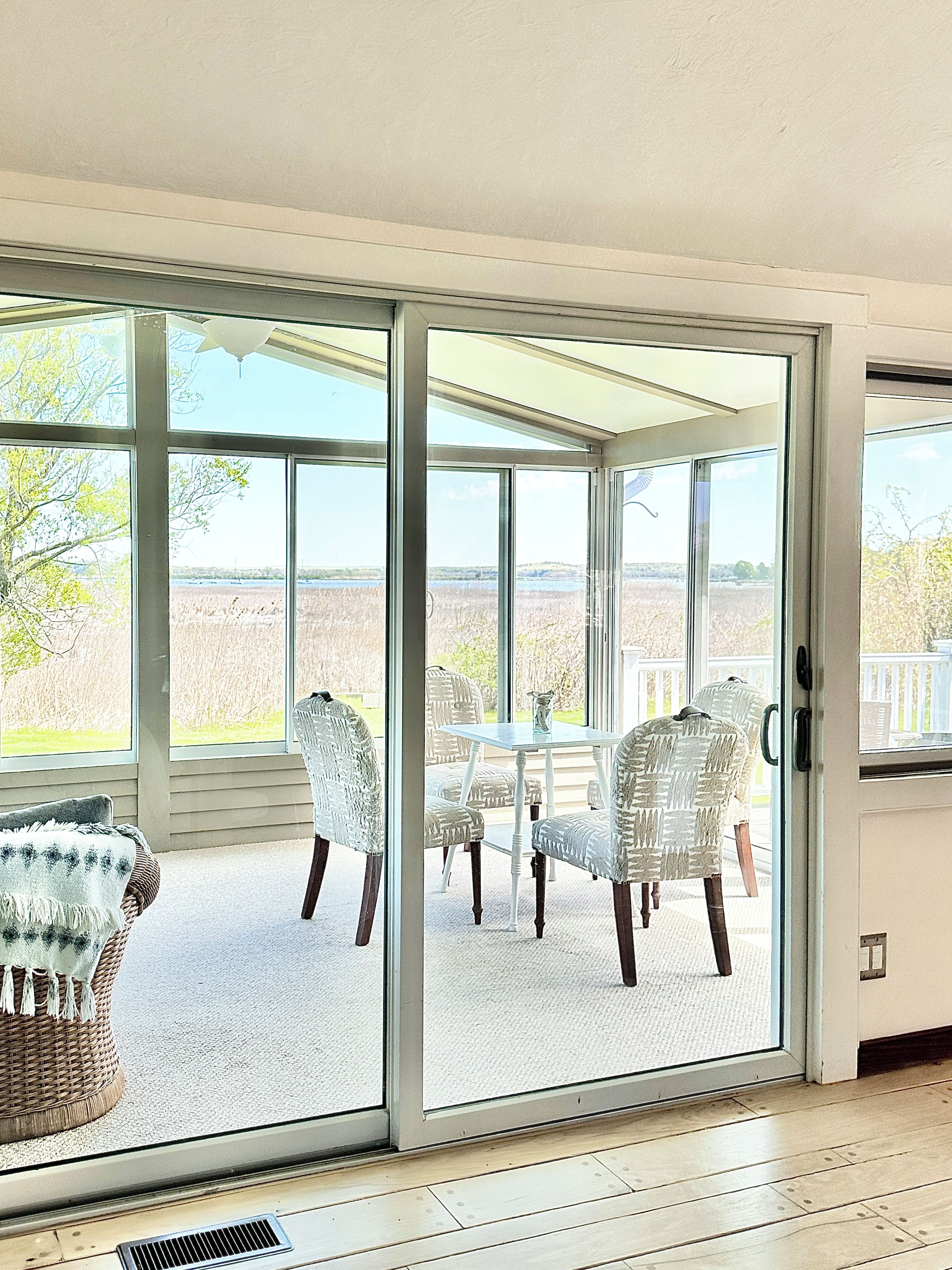 A room with a sliding glass door leading to an outdoor patio with wicker furniture and a table.