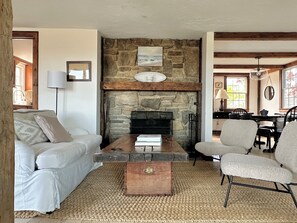 A cozy living room with a stone fireplace, a wooden coffee table, and a comfortable sofa.