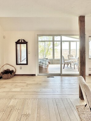 A spacious room with a large sliding glass door leading to an outdoor area with wicker furniture.