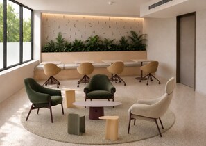Ein moderner Lounge-Bereich mit runden Tischen und Sesseln, einer niedrigen Wand mit Pflanzen und einem großen Fenster, das für natürliches Licht sorgt.