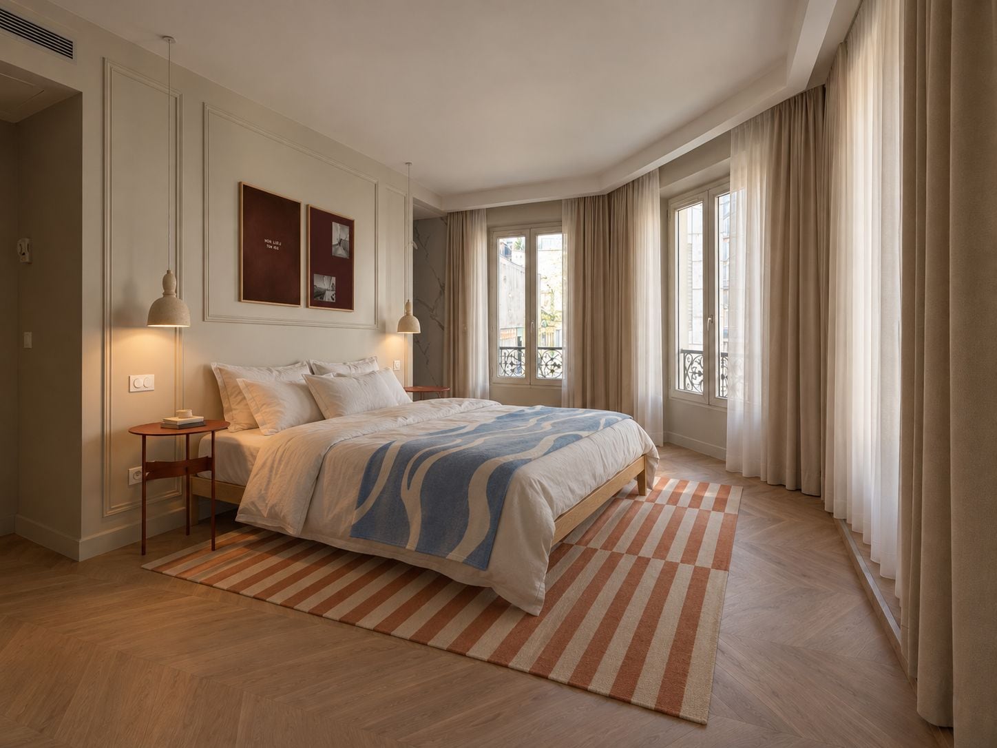 Un dormitorio con una cama grande, una mesita de noche, una silla, una alfombra y una ventana con cortinas.