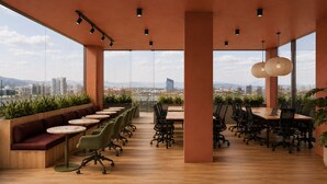 A modern office space with a long table, chairs, and a seating area with a view of the cityscape. - Outsite Paris - Bastille - Work, Connect, Explore. (Paris)