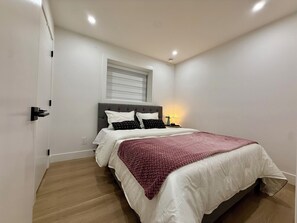A bedroom with a bed, bedside table, and a window with blinds.