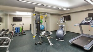 A gym with exercise equipment, a treadmill, and a weight bench.