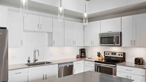 A modern kitchen with white cabinets, stainless steel appliances, a dishwasher, and a coffee maker.