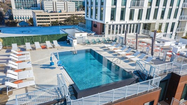 A rooftop pool with lounge chairs and a view of surrounding buildings.