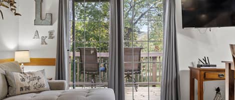 Un salon comprenant un canapé, une table basse, un téléviseur et une porte-fenêtre coulissante donnant sur une terrasse extérieure.