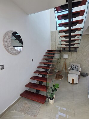 Ein modernes Interieur mit einer Wendeltreppe, einem runden Spiegel und einer Sitzecke mit einer Lampe.