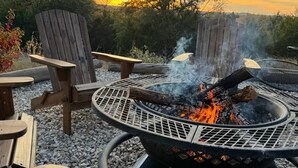A fire pit with a metal grill and a wooden chair. - "The Ft Worth" Romantic Tiny Home Near Wineries (Weatherford)