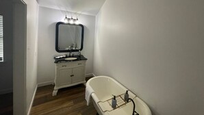 Une salle de bain avec un meuble-lavabo blanc, un miroir, une baignoire et une poutre en bois au plafond.