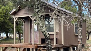 Une cabane en bois avec une véranda, une porte et une fenêtre.