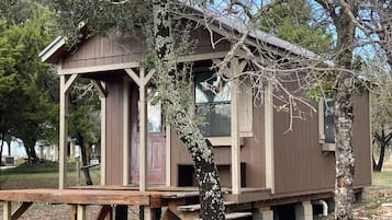 A wooden cabin with a porch, a door, and a window.