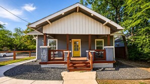 A single-story building with a porch, a yellow door, and a small set of stairs leading to the entrance. - Fireplace~Outdoor Games~Near Downtown~Grill (San Antonio)