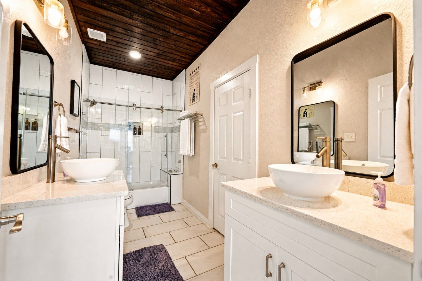 Un baño moderno con dos lavamanos grandes de color blanco, una cabina de ducha con mampara de cristal y techo de madera.