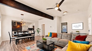 A spacious living room with a sofa, coffee table, and dining area. - Fireplace~Outdoor Games~Near Downtown~Grill (San Antonio)