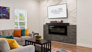 A modern living room with a fireplace, a sofa, a coffee table, and a painting on the wall. - Fireplace~Outdoor Games~Near Downtown~Grill (San Antonio)