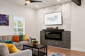 Una sala de estar moderna con chimenea, un sofá, una mesa de centro y un cuadro en la pared.